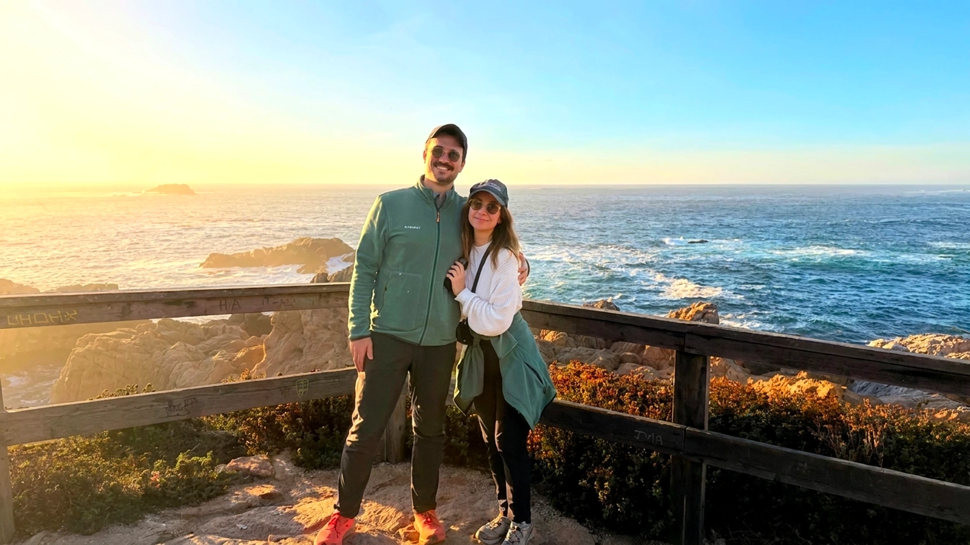Morgan and Spencer in hats with the ocean behind them in Carmel